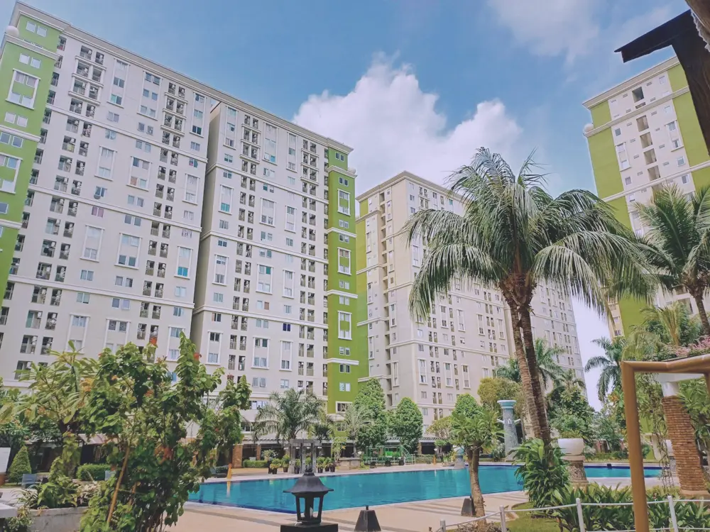 Piscina comunitaria con palmeras frente a un edificio de viviendas